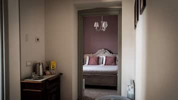 Una habitación de hotel con una cama, un escritorio con hervidor, una silla y una mesita.