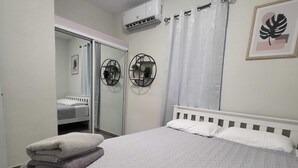 A neatly arranged bedroom with a bed, a wardrobe, and a mirror. - D'lujo Apt. #2 con A/C, Wi-Fi & Parking (Vega Baja)