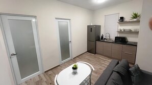 A compact kitchen with a refrigerator, microwave, and sink. There is a small dining table with a potted plant. - D'lujo Apt. #2 con A/C, Wi-Fi & Parking (Vega Baja)