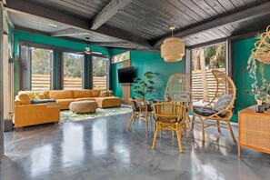 Relax in a spacious living area with a sofa set, dining table, and mounted TV.