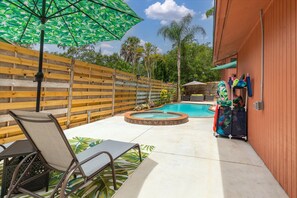 Relax by the pool surrounded by a patio area and a wooden fence.