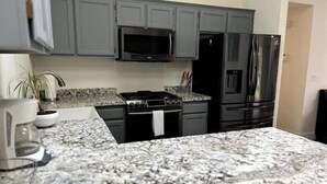 A kitchen with grey cabinets, a black microwave, a black stove, and a black refrigerator. - The Bluff House~Upgraded & Close to Town (McKinleyville)