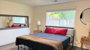A bedroom with a bed, a window, a mirror, and a nightstand. - The Bluff House~Upgraded & Close to Town (McKinleyville)
