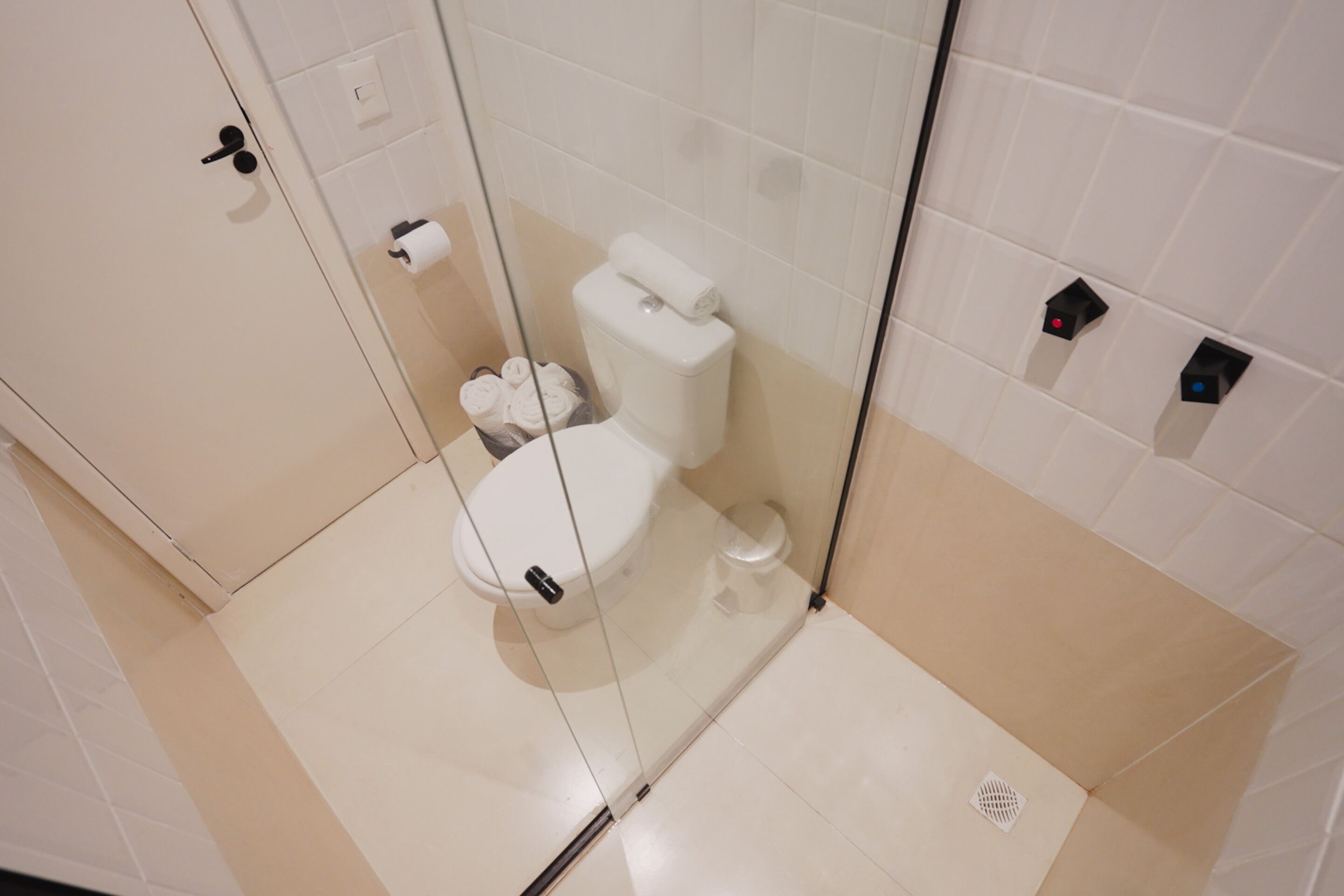 A modern bathroom with a toilet, a glass shower enclosure, and a toilet paper holder.
