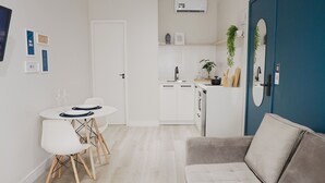 A modern living room with a grey sofa, a dining table with chairs, and a kitchen area with a sink and cabinets. - Apê Metrô Paraíso (São Paulo)