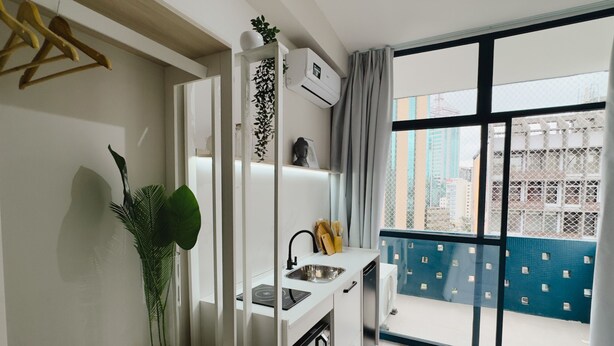 A modern kitchen with a built-in oven, a sink, and a window overlooking a cityscape. - Apê Metrô Paraíso (São Paulo)