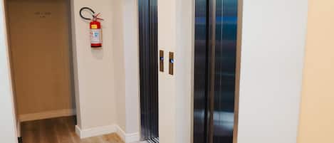 A hallway with an elevator, a fire extinguisher, and a door marked 101-106.