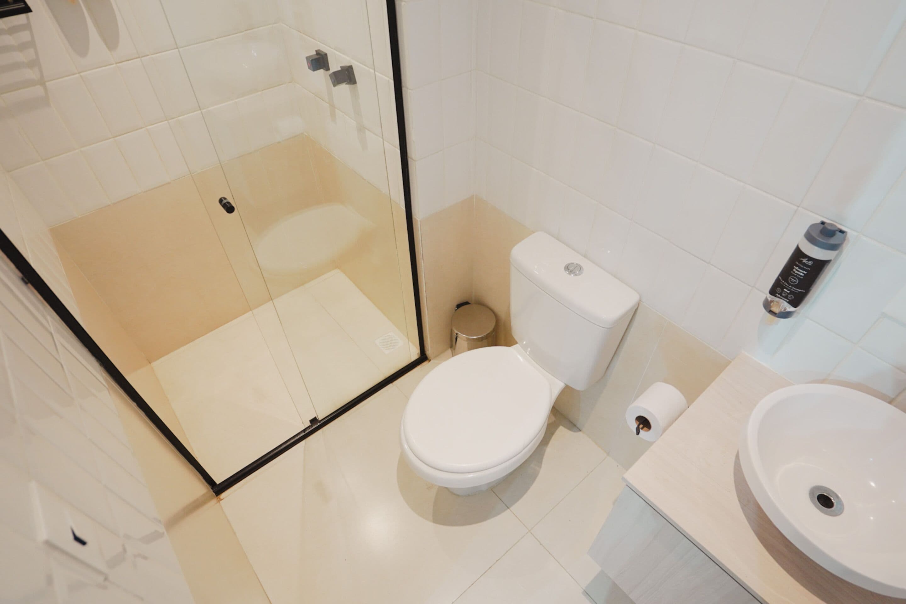 Un baño moderno con ducha envuelta en vidrio, inodoro y lavabo.