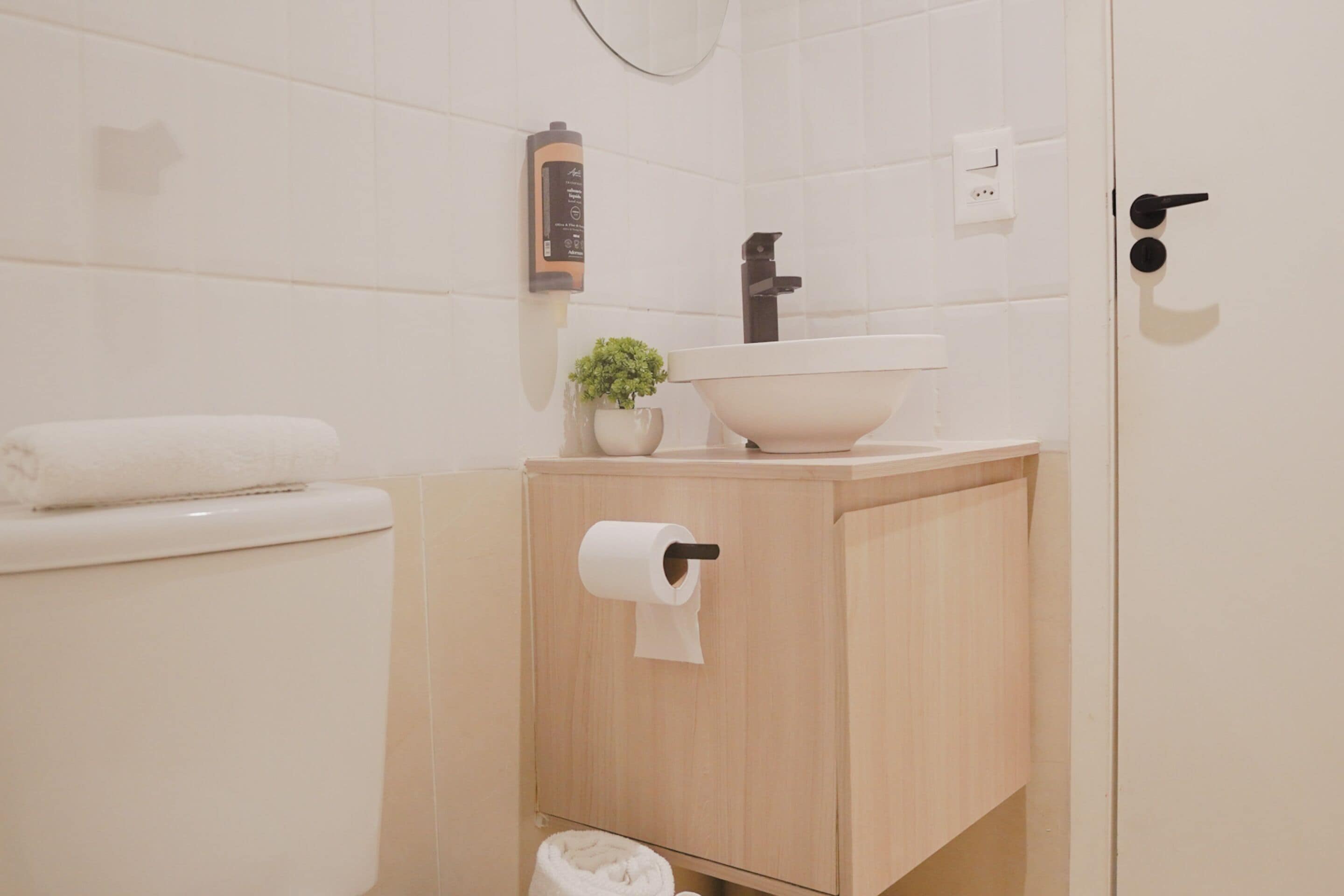 A bathroom with a toilet, sink, and a small plant on the counter.