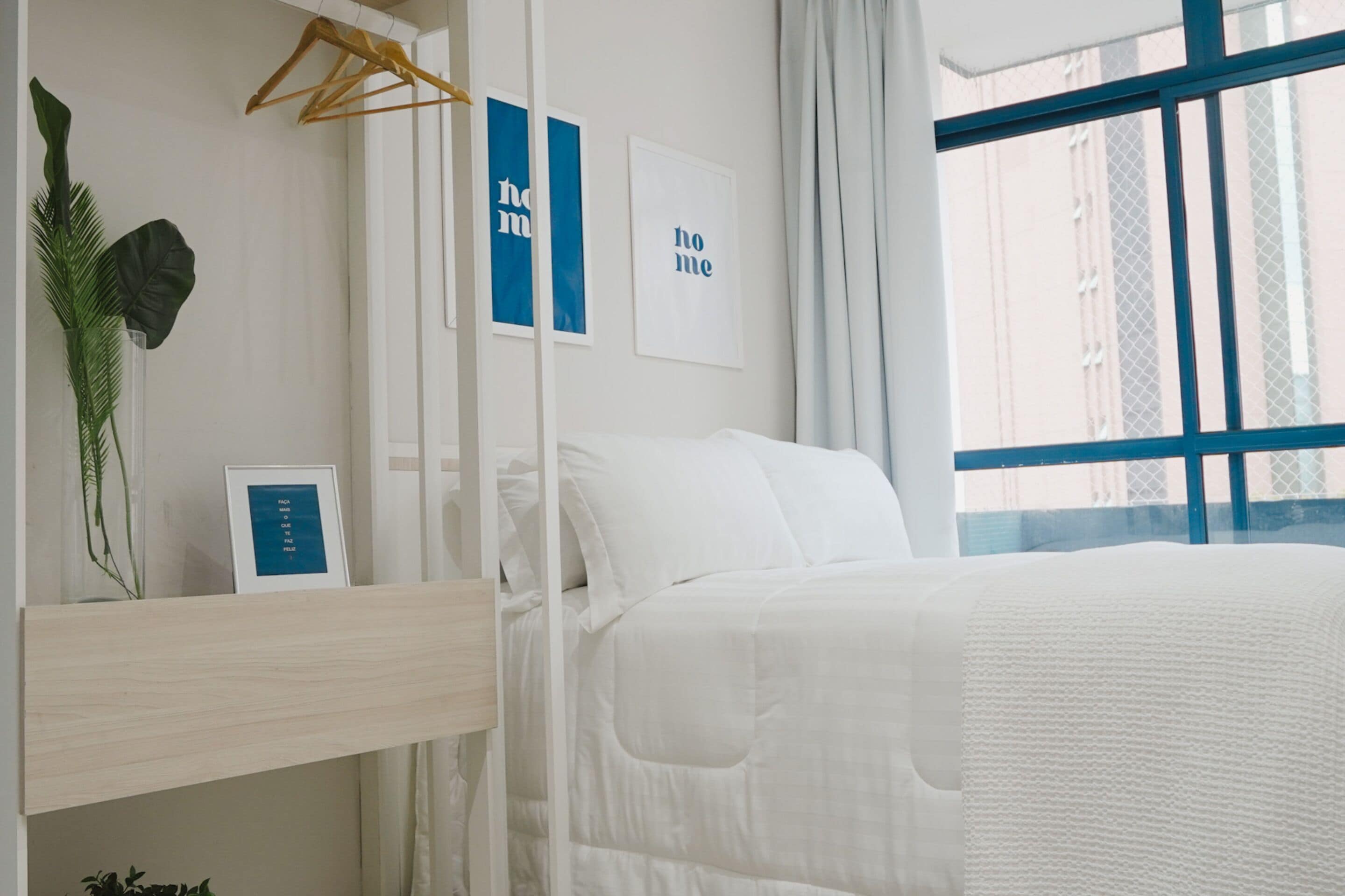 A neatly arranged bedroom with a bed, a bedside table, and a window with a view of buildings.