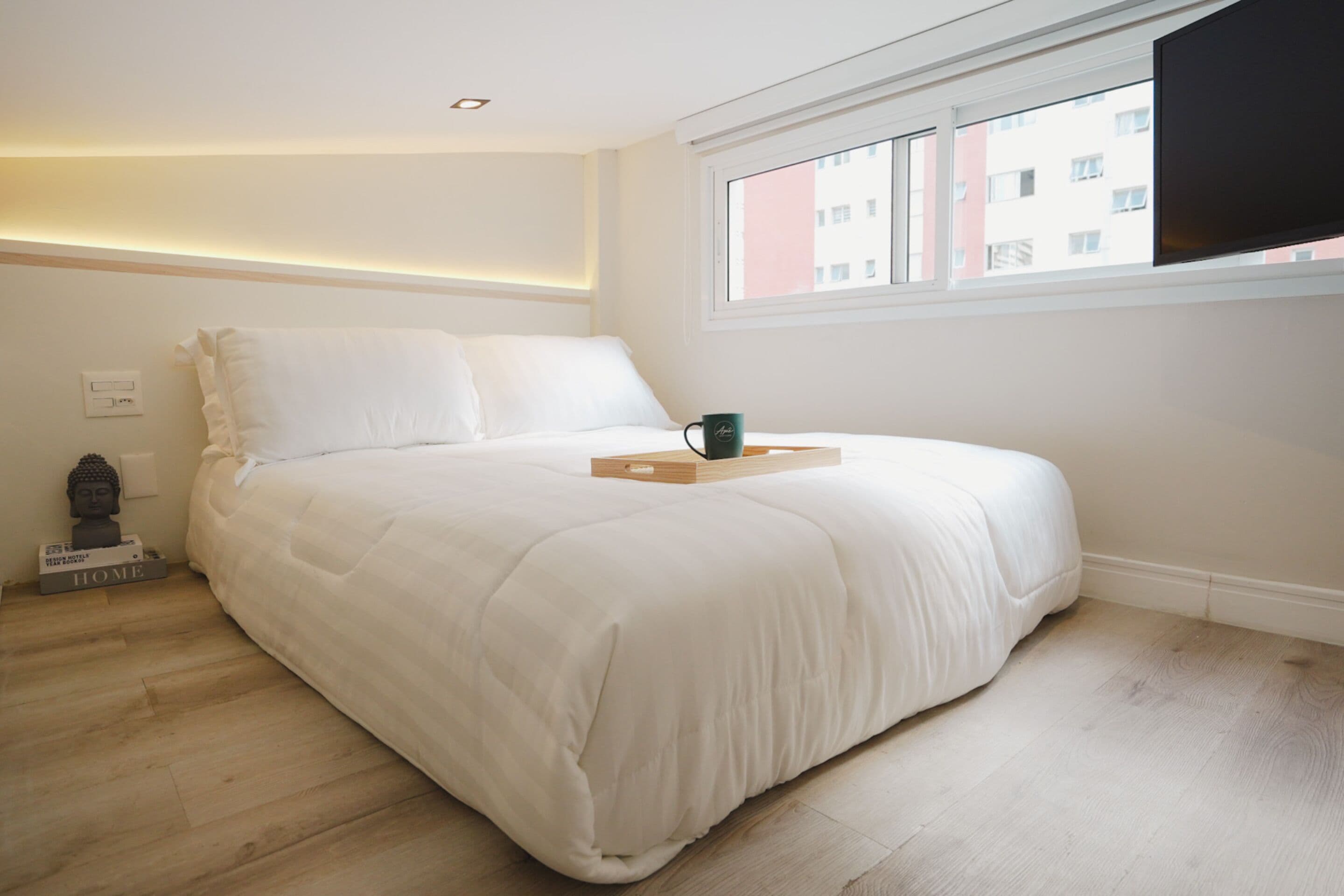 A bedroom with a large bed, a window, and a flat-screen TV.