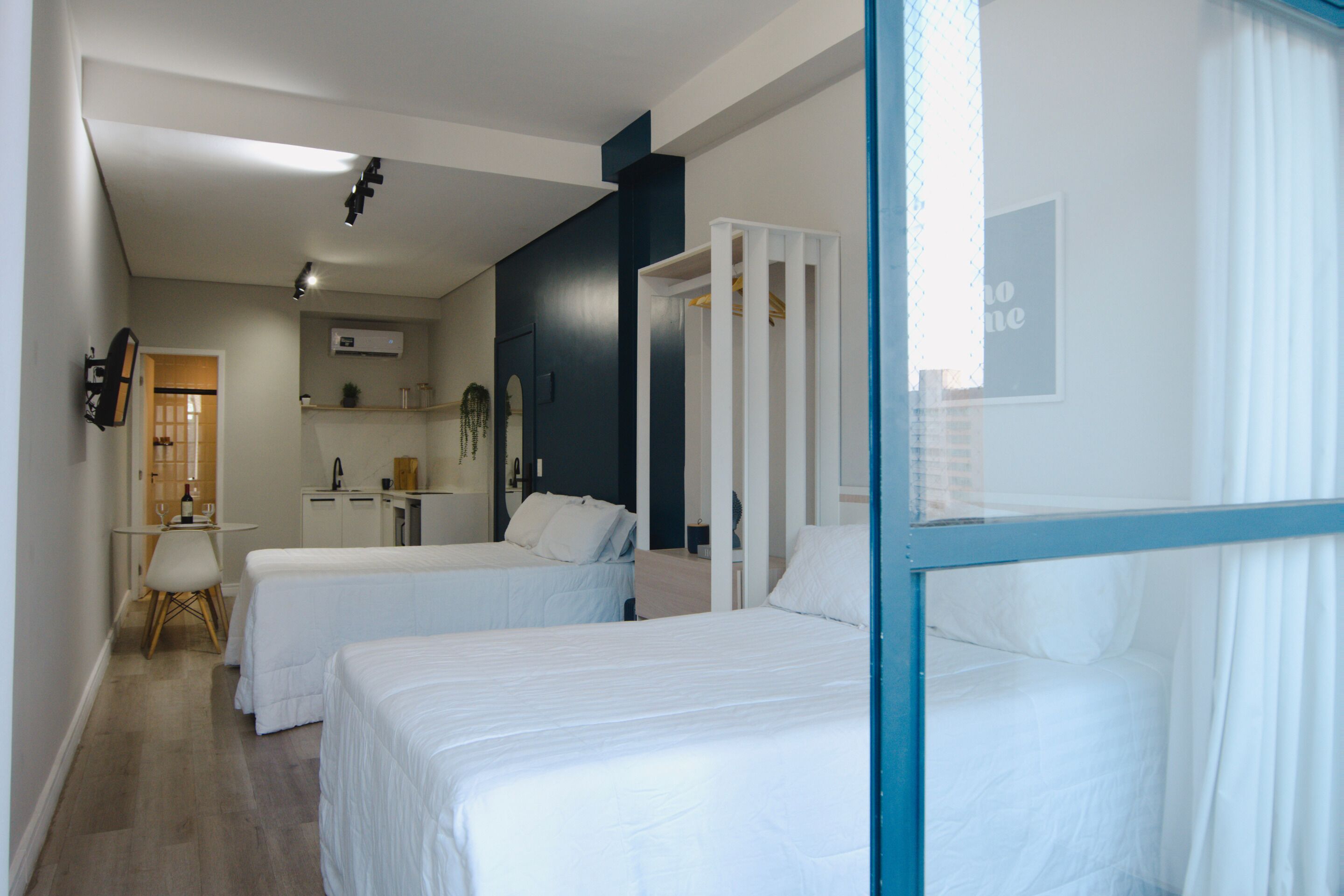 A hotel room with two beds, a desk, a chair, a wardrobe, and a bathroom.