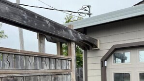 Une porte en bois donne accès à un garage dont l’extérieur est gris et la porte est blanche.