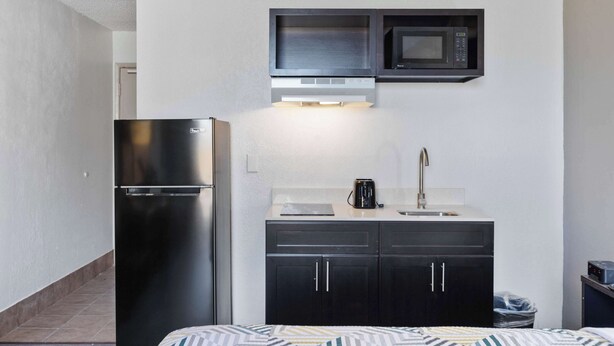 A compact kitchenette with a stainless steel refrigerator, a microwave, a sink, and a coffee maker. - Studio 6 Pecos, Tx (Pecos)