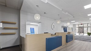 A reception area with a wooden reception desk, a blue counter, and a number '6' on the wall. - Studio 6 Pecos, Tx (Pecos)