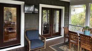 Une véranda avec une chaise en osier, une table à manger avec des chaises et un ventilateur de plafond.