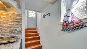 Une cuisine dotée d’un plan de travail en granit et d’un escalier en bois menant à une porte.