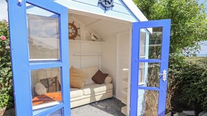 Une petite structure de couleur bleue, sur le thème de la marine, dotée d’un intérieur accueillant, avec un banc rembourré et un volant décoratif.