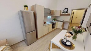 Une cuisine compacte équipée d’un réfrigérateur, d’un four et d’un évier. Un petit coin repas avec une table et des chaises est également disponible.