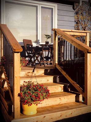 Eine Holzterrasse mit Treppe, Gartenmöbeln und einem hängenden Blumentopf.