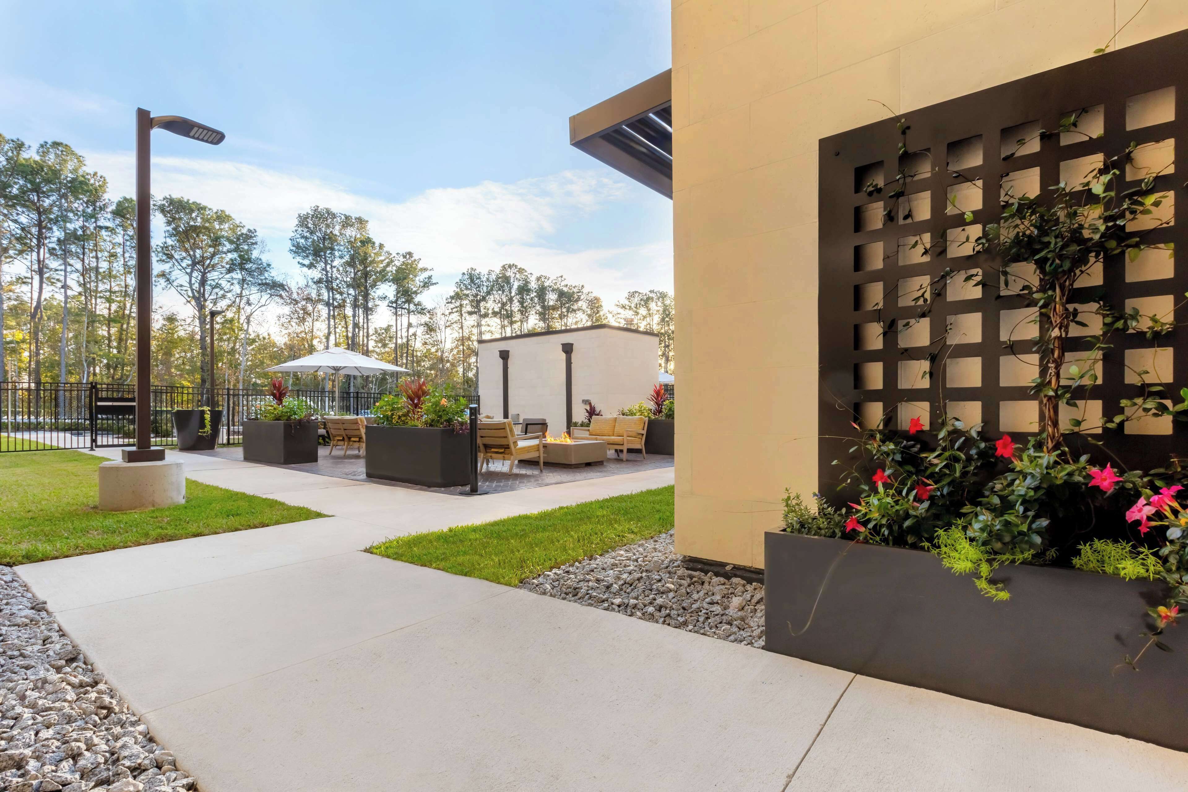 A patio area with outdoor seating, a fire pit, and a pergola with climbing plants.