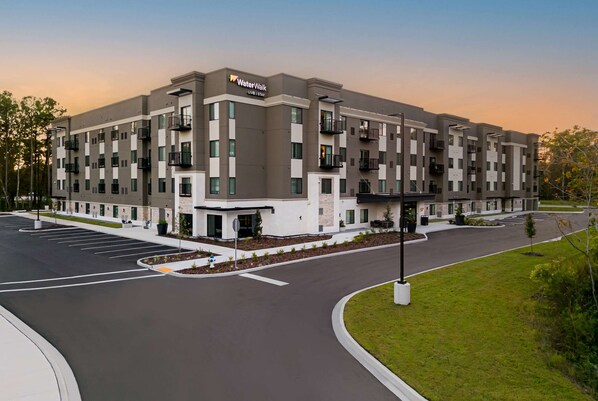 A multi-story hotel with a modern design, featuring balconies, a parking lot, and landscaped areas. - WaterWalk Extended Stay by Wyndham Jacksonville Deerwood Pk (Jacksonville)