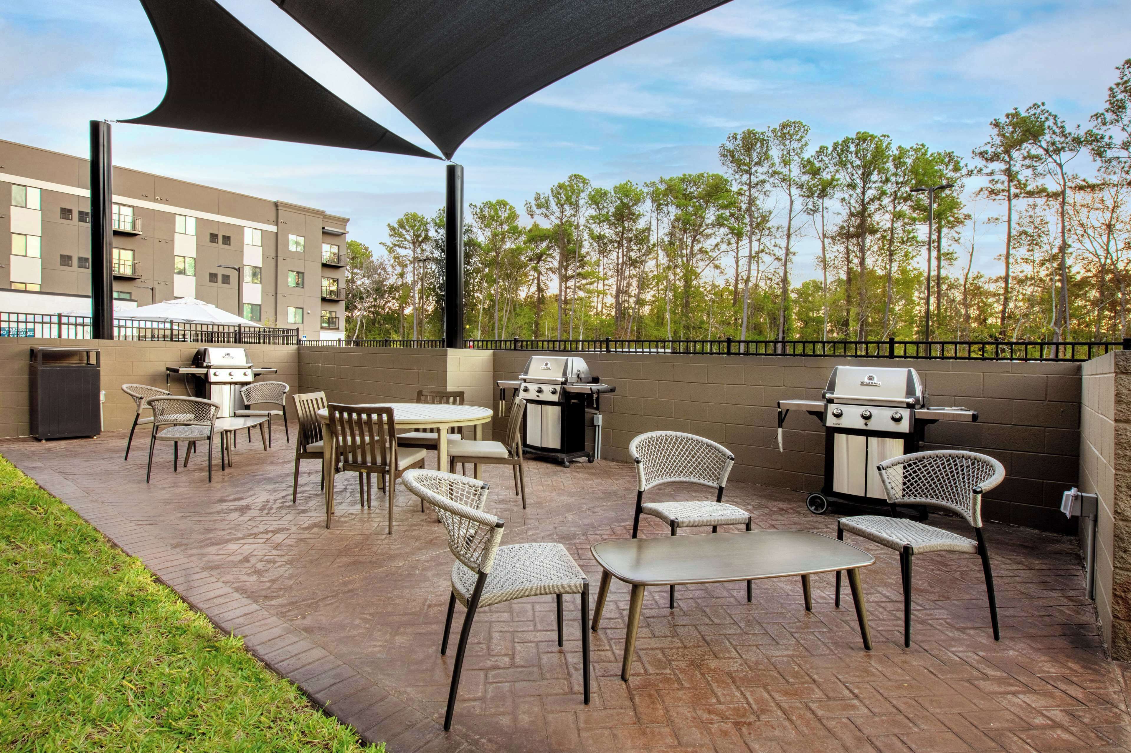 An outdoor patio with a grill, tables, and chairs.