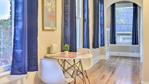 A room with a round table, two chairs, a potted plant, and a framed picture on the wall. - Historic 1925 Apt Near Downtown! (Raleigh)