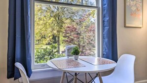 A room with a window, a table with a plant, and two chairs. - Historical 1BR Apt in Glenwood (Raleigh)