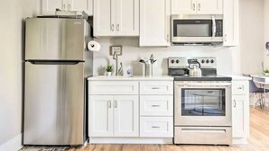 A modern kitchen with white cabinetry, stainless steel appliances, and a wooden floor. - Historical 1BR Apt in Glenwood (Raleigh)