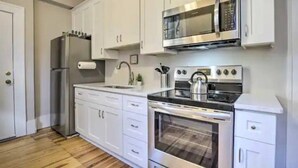 Une cuisine moderne avec des armoires blanches, des appareils en acier inoxydable et un plancher en bois.