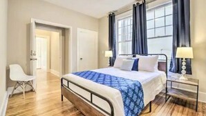 Une chambre d’hôtel avec un lit, une chaise, une table de chevet et une fenêtre avec des rideaux.