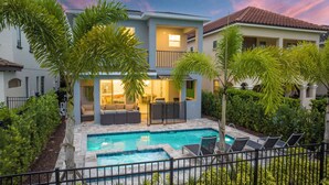 A two-story house with a swimming pool, outdoor seating, and lush greenery. - Luxury Oasis near Disney - Pool, Spa & Game Rooms - POOL HEAT & BBQ FREE! (Orlando)