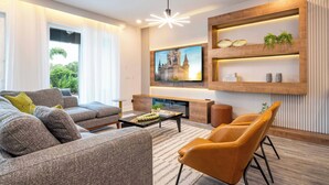 Ein modernes Wohnzimmer mit einer Couch, einem Couchtisch und einem an der Wand befestigten Fernseher.