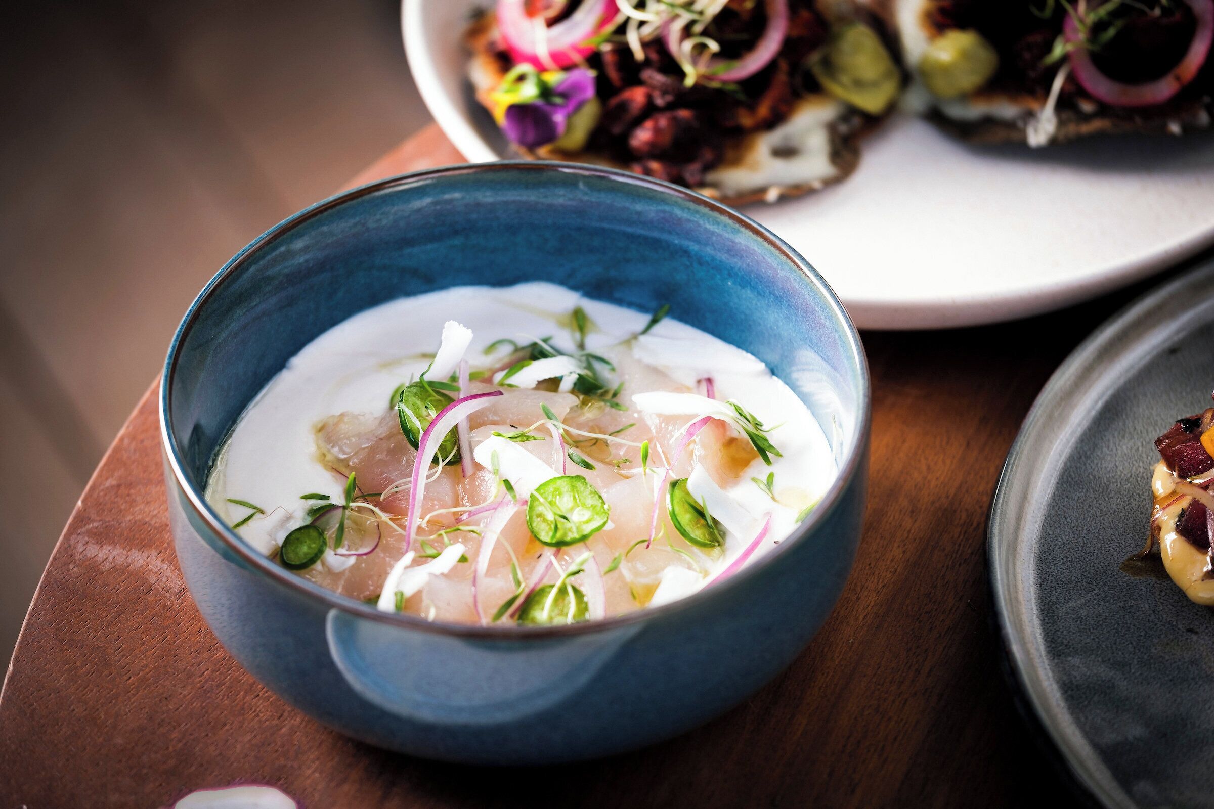 A bowl of food with various toppings, placed on a wooden table.