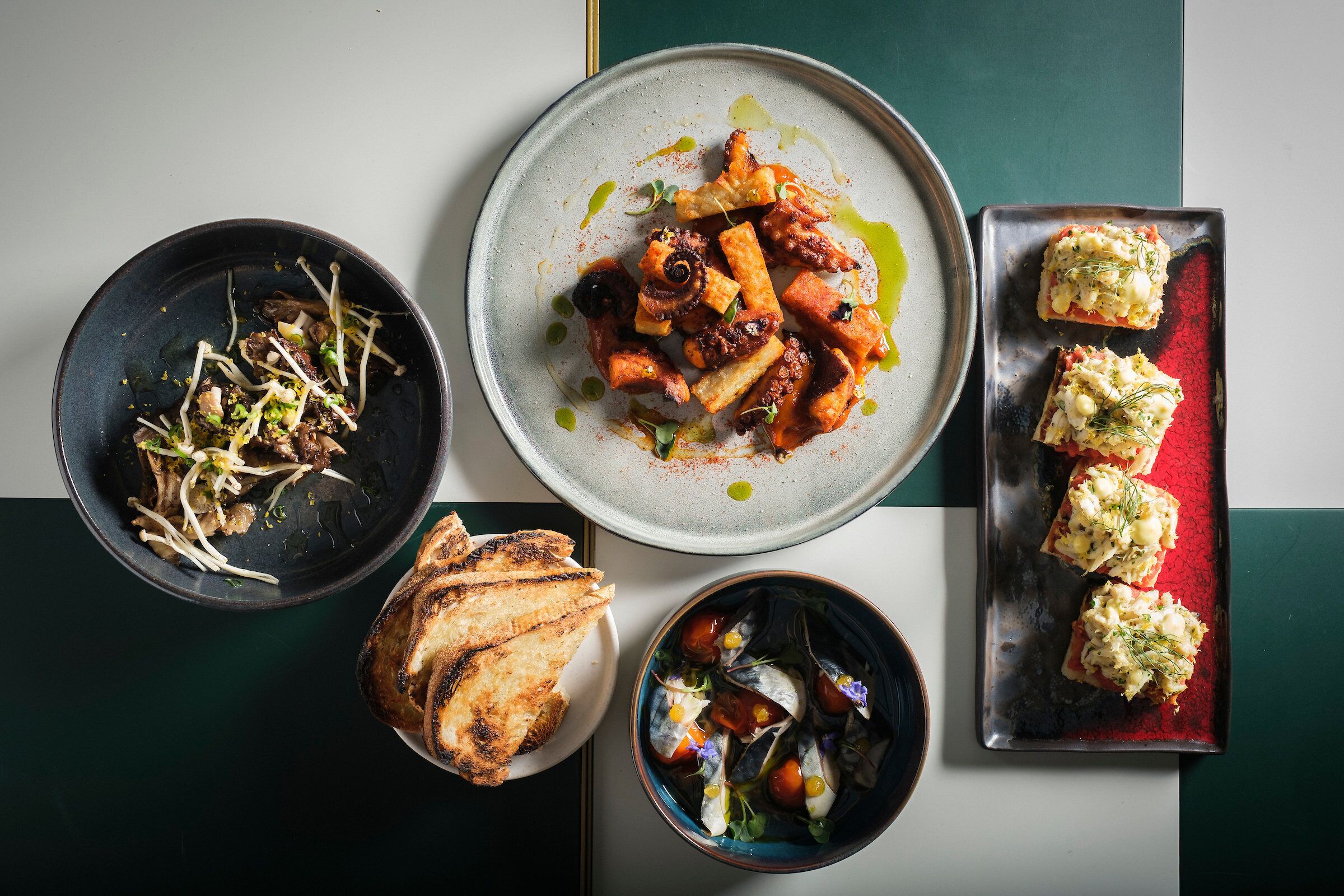 A variety of dishes including grilled meat, vegetables, and bread on a table.