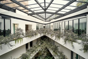 A modern building interior with a central atrium, glass ceiling, and extensive greenery. - Kimpton Virgilio Polanco by IHG (Mexico City)