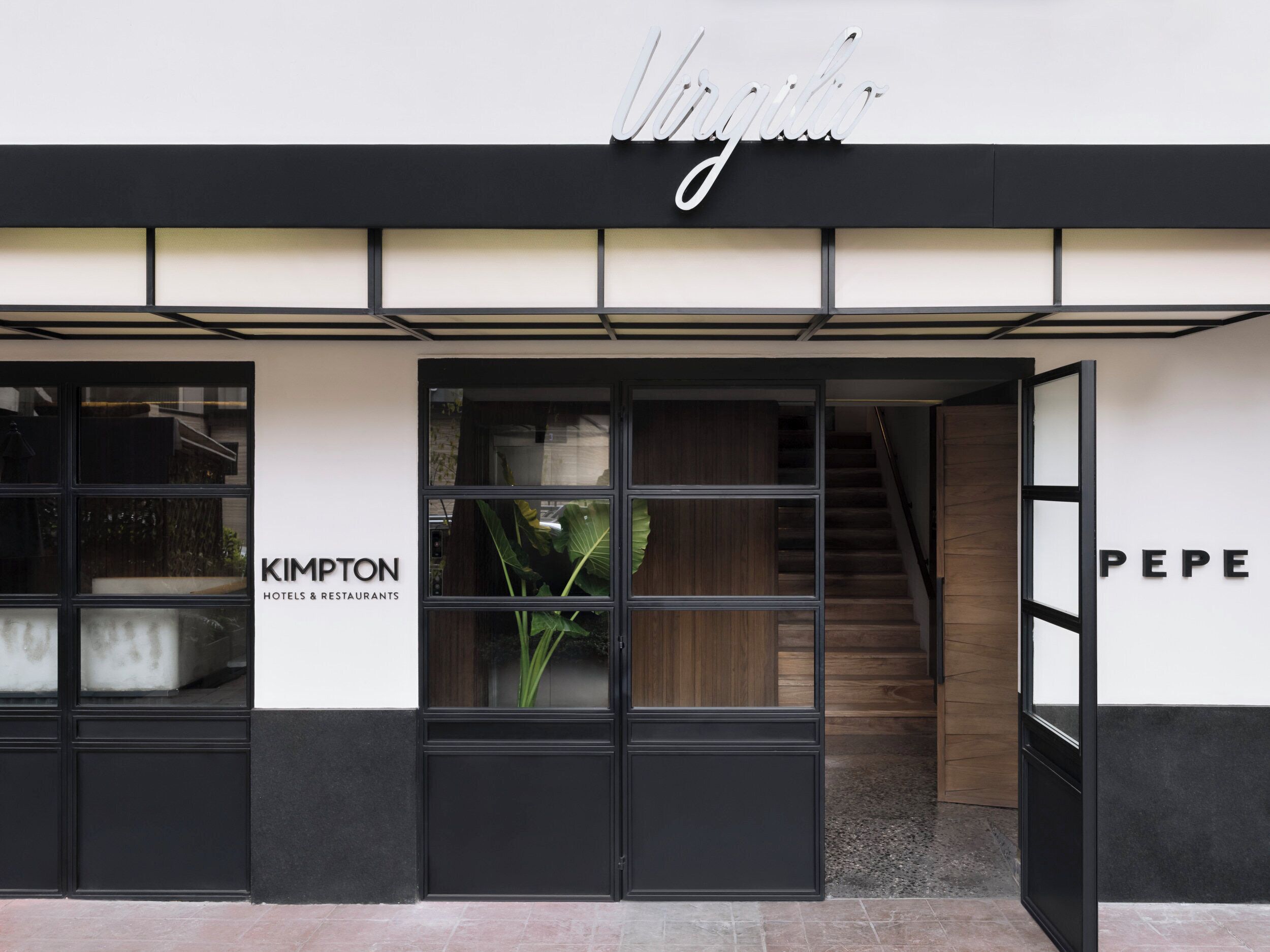 A modern hotel entrance with a black and white facade, a staircase, and glass doors.