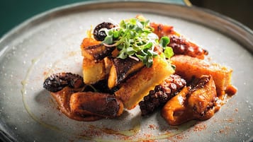 Un plato de comida con diversos tipos de carne y verduras, adornado con brotes micro.
