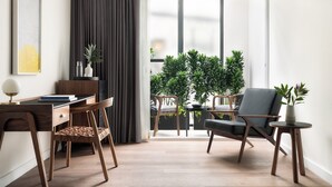 A modern living room with a wooden desk, two chairs, a small table, and a potted plant. - Kimpton Virgilio Polanco by IHG (Mexico City)