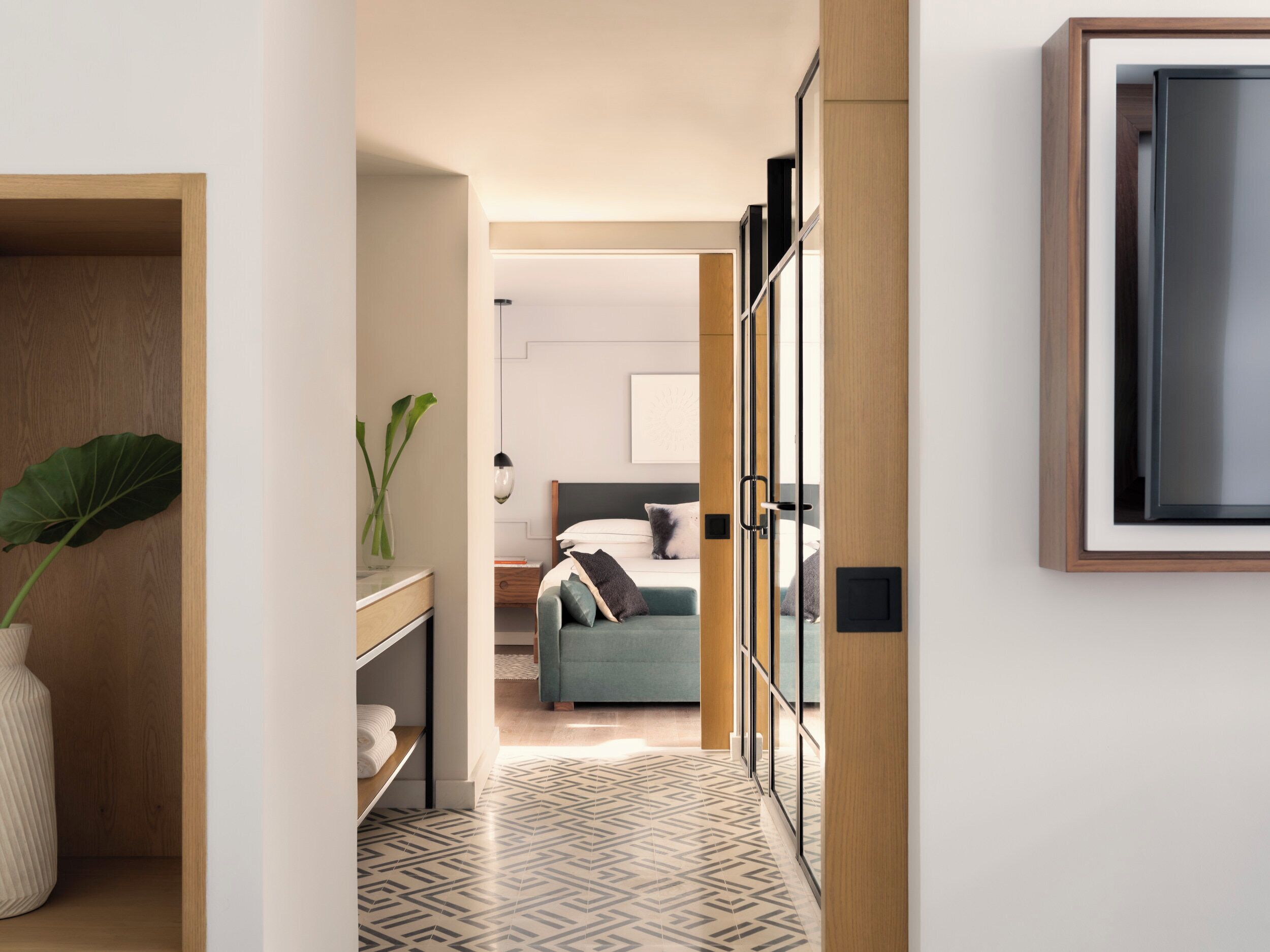 A modern hotel room with a bed, bedside table, and a large window.