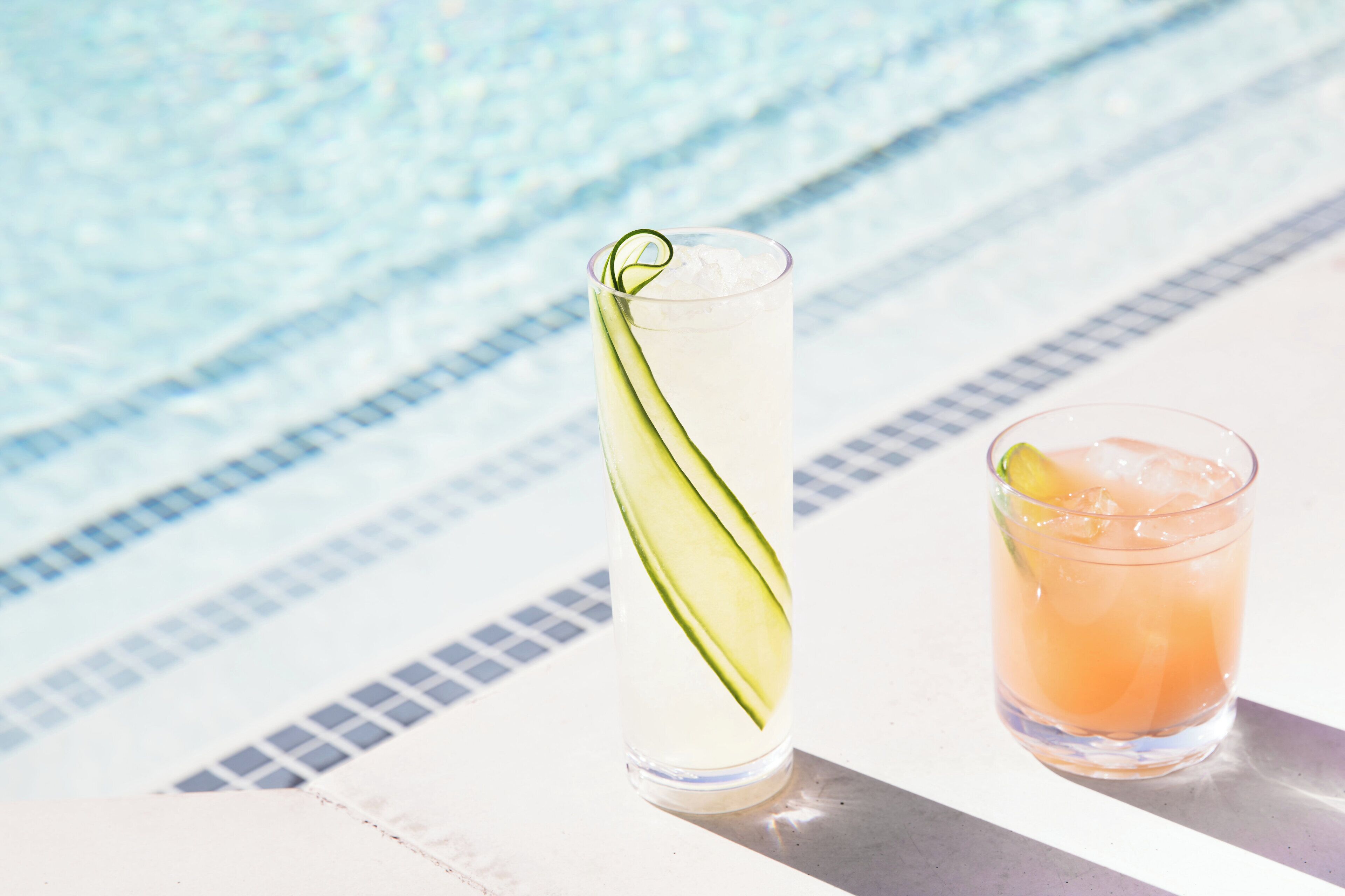 Zwei Getränke auf einem Tisch am Pool, im Hintergrund ein Schwimmbecken.