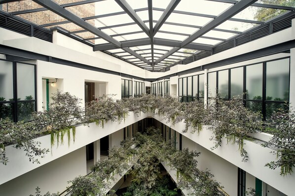 Un edificio moderno con un atrio central, ventanas amplias y vegetación.