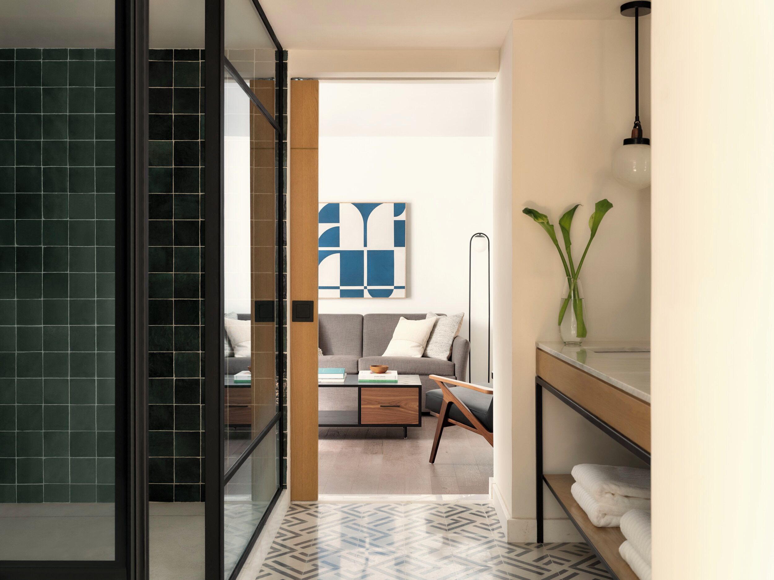 Un baño moderno con cabina de ducha de vidrio, tocador de madera y un espejo grande.