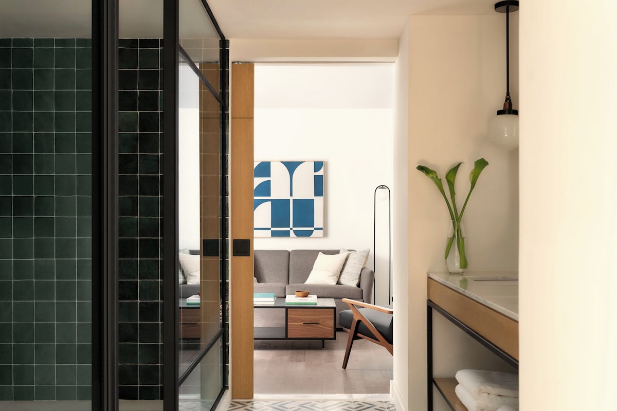 A modern bathroom with a glass shower enclosure, a wooden vanity, and a large mirror.