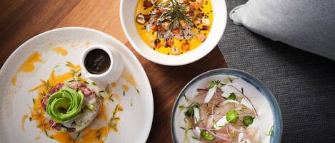 Three dishes on a wooden table with a grey couch in the background.