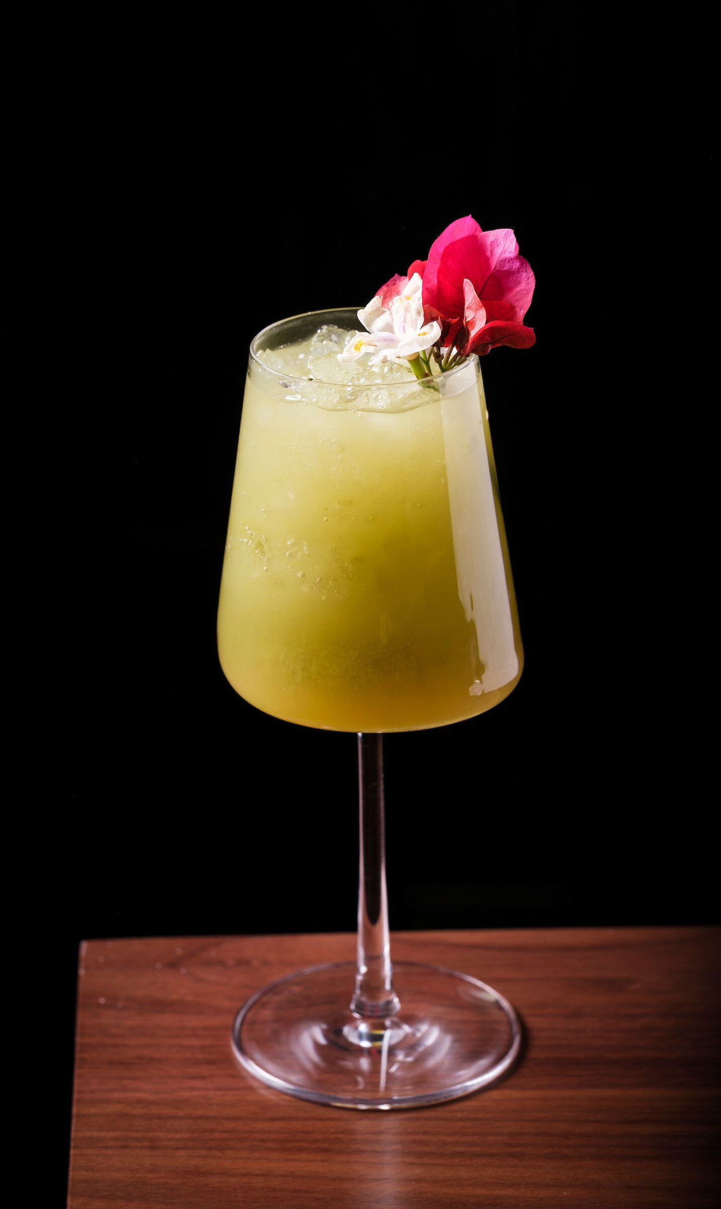 A cocktail in a stemmed glass with a flower garnish.