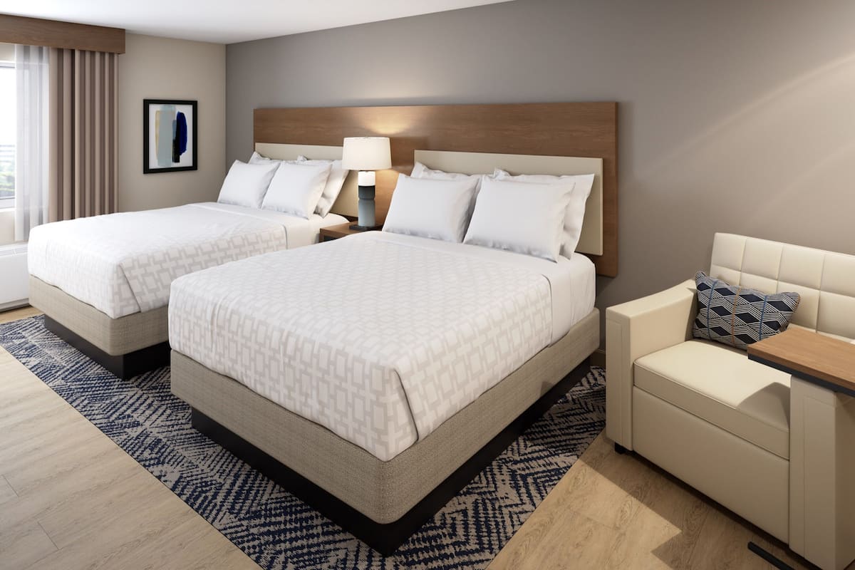 Een hotelkamer met twee bedden, een bank, een nachtkastje en een lamp.