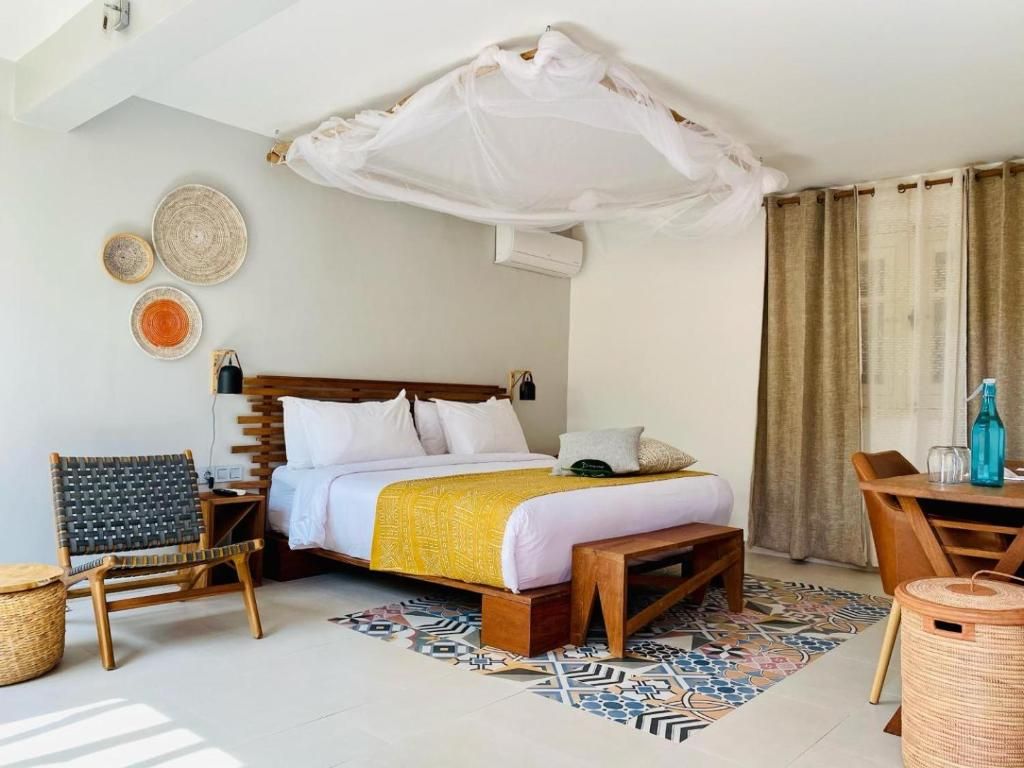 Una habitación de hotel con una cama, una silla, una mesa, un banco y un muro decorativo.