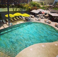 A clear swimming pool with sun loungers and yellow umbrellas.